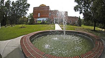 A brick fountain with a building in the background.